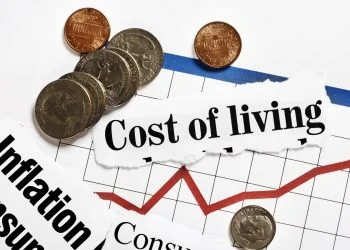 Coins rest on rising graph and cost of living headlines