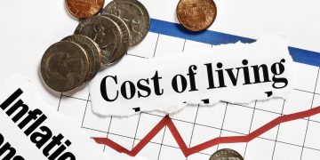 Coins rest on rising graph and cost of living headlines