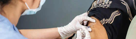 doctor in gloves holding syringe and making injection to senior patient in medical mask