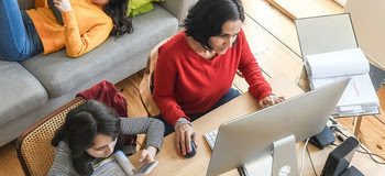 woman working at home in living room, daughters doing home work and hanging around