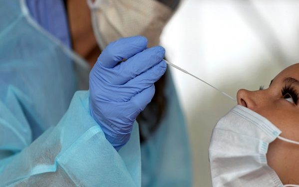 BROCKTON - AUGUST 13: A nurse practitioner administers COVID-19 tests in the parking lot at Brockton High School in Brockton, MA under a tent during the coronavirus pandemic on Aug. 13, 2020. (Photo by David L. Ryan/The Boston Globe via Getty Images)