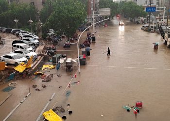 People wade through floodwaters on a road amid heavy rainfall in Zhengzhou, Henan province, China July 20, 2021. Picture taken July 20, 2021. China Daily via REUTERS  ATTENTION EDITORS - THIS IMAGE WAS PROVIDED BY A THIRD PARTY. CHINA OUT.