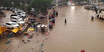 People wade through floodwaters on a road amid heavy rainfall in Zhengzhou, Henan province, China July 20, 2021. Picture taken July 20, 2021. China Daily via REUTERS  ATTENTION EDITORS - THIS IMAGE WAS PROVIDED BY A THIRD PARTY. CHINA OUT.