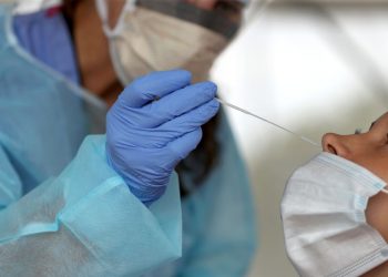 BROCKTON - AUGUST 13: A nurse practitioner administers COVID-19 tests in the parking lot at Brockton High School in Brockton, MA under a tent during the coronavirus pandemic on Aug. 13, 2020. (Photo by David L. Ryan/The Boston Globe via Getty Images)