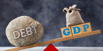 Debt-to-GDP ratio, a large stone with text DEBT and wooden cubes with GDP letters and bag on seesaw