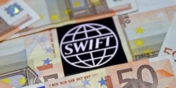 FILE PHOTO: Swift code bank logo is displayed on an iPhone 6s among Euro banknotes in this picture illustration January 26, 2016.  REUTERS/Dado Ruvic/File Photo