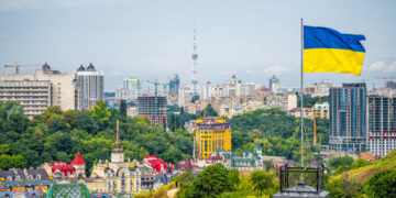 Kyiv, Ukraine cityscape of Kiev and Ukrainian flag waving in the wind during summer in Podil district and colorful new buildings