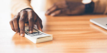 Venality Concept. Unrecognizable african businessman holding bunch of hundred dollar bills, copy space, panorama