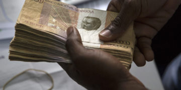 A worker counts 500 denomination kwanza currency banknotes in an office in Luanda, Angola, on Friday, Nov. 8, 2013. Angola, the largest crude oil producer in Africa after Nigeria, appointed Deloitte LLP as the independent auditor of its $5 billion sovereign wealth fund to ensure transparency. Photographer: Simon Dawson/Bloomberg