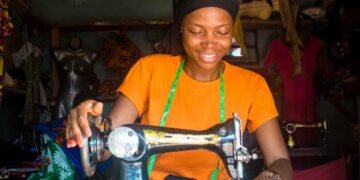 portrait of a young african female tailor smiling while working with her sewing machine