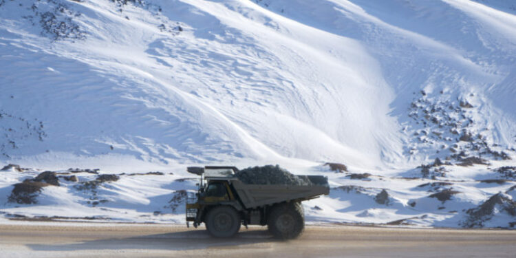 Dump truck loaded with ore driving through a snow covered open pit mine