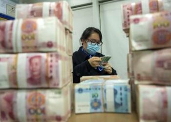 A clerk counts renminbi banknotes at a bank outlet in Hai'an city in eastern China's Jiangsu province,  Monday, Dec. 6, 2021 China's central bank is trying to restrain the rise of the yuan after the currency hit a 2 1/2-year high against the dollar. (Chinatopix Via AP)