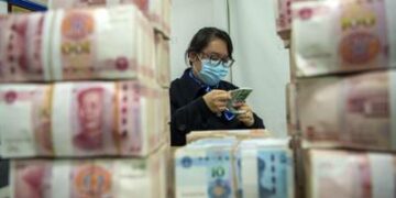 A clerk counts renminbi banknotes at a bank outlet in Hai'an city in eastern China's Jiangsu province,  Monday, Dec. 6, 2021 China's central bank is trying to restrain the rise of the yuan after the currency hit a 2 1/2-year high against the dollar. (Chinatopix Via AP)