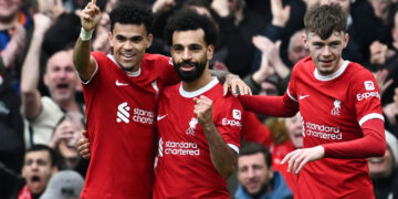 Liverpool's Egyptian striker #11 Mohamed Salah (C) celebrates after scoring his team second goal during the English Premier League football match between Liverpool and Brighton and Hove Albion at Anfield in Liverpool, north west England on March 31, 2024. (Photo by Paul ELLIS / AFP) / RESTRICTED TO EDITORIAL USE. No use with unauthorized audio, video, data, fixture lists, club/league logos or 'live' services. Online in-match use limited to 120 images. An additional 40 images may be used in extra time. No video emulation. Social media in-match use limited to 120 images. An additional 40 images may be used in extra time. No use in betting publications, games or single club/league/player publications. / (Photo by PAUL ELLIS/AFP via Getty Images)