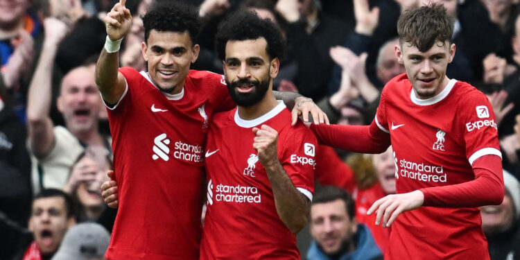 Liverpool's Egyptian striker #11 Mohamed Salah (C) celebrates after scoring his team second goal during the English Premier League football match between Liverpool and Brighton and Hove Albion at Anfield in Liverpool, north west England on March 31, 2024. (Photo by Paul ELLIS / AFP) / RESTRICTED TO EDITORIAL USE. No use with unauthorized audio, video, data, fixture lists, club/league logos or 'live' services. Online in-match use limited to 120 images. An additional 40 images may be used in extra time. No video emulation. Social media in-match use limited to 120 images. An additional 40 images may be used in extra time. No use in betting publications, games or single club/league/player publications. / (Photo by PAUL ELLIS/AFP via Getty Images)