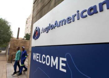 Visitors pass a sign at the entrance to the offices of Anglo American Plc in the Marshalltown district of Johannesburg, South Africa, on Friday, Oct. 26, 2012. Anglo American Plc Chief Executive Officer Cynthia Carroll , the first woman, external hire and non-South African to hold the job, will quit after Anglo lost $14 billion in value in the more than five years she was in charge. Photographer: Chris Ratcliffe/Bloomberg via Getty Images