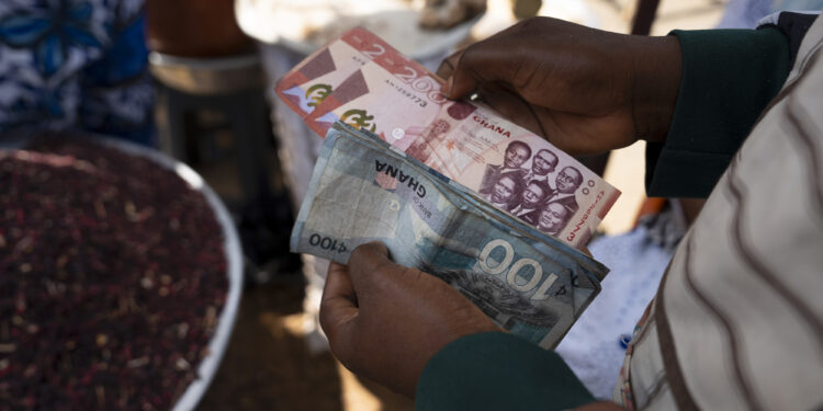 A customer counts Ghana cedi banknotes at the Nima market in Accra, Ghana on Monday, March 11, 2024