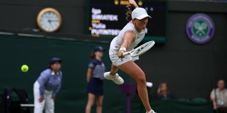 Poland's Iga Swiatek misses a return against Kazakhstan's Yulia Putintseva during their women's singles tennis match on the sixth day of the 2024 Wimbledon Championships at The All England Lawn Tennis and Croquet Club in Wimbledon, southwest London, on July 6, 2024. Putintseva won the third round match 3-6, 6-1, 6-2. (Photo by HENRY NICHOLLS / AFP) / RESTRICTED TO EDITORIAL USE