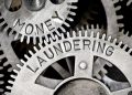Macro photo of tooth wheel mechanism with MONEY LAUNDERING letters imprinted on metal surface