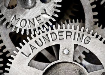 Macro photo of tooth wheel mechanism with MONEY LAUNDERING letters imprinted on metal surface
