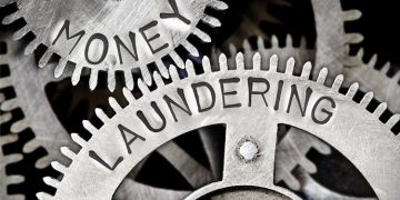 Macro photo of tooth wheel mechanism with MONEY LAUNDERING letters imprinted on metal surface