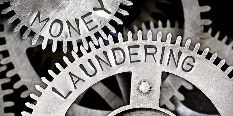 Macro photo of tooth wheel mechanism with MONEY LAUNDERING letters imprinted on metal surface